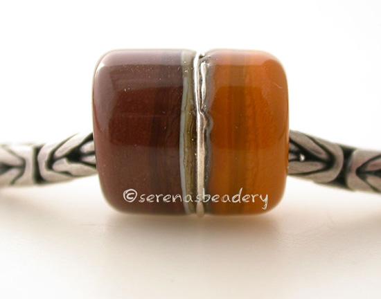 Chocolate Butternut European Charm with Fine Silver One European charm style bracelet bead with chocolate brown and butternut yellow, silvered ivory, and fine silver. Bead Size: approximately 14x12 mm Amount: 1 Bead Hole Size: 5 mm Glossy,Matte