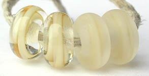 Ivory Ribbon Color Notes: ivory ribbon cased in clear 5x10 mm Donut- This is my basic spacer size. It is made on a 3/32 mandrel with a 2.5 mm hole. Other available sizes and shapes: 4x8 mm Round- A miniature sized spacer with a 1.5 mm hole. Lentil- 12x13 mm in size with a 1.5mm hole. Pillow- 14 mm square with a 1.5 mm hole. Disk- 3x13 mm with a 2.5 mm hole. Also 6x12 mm donut- A larger donut with a 2.5 mm hole. 8x15 mm Super Sized- A humungous spacer with a 3.5 mm hole. It is perfect for stringing on leathe