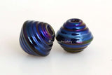 Black Iris Ribbed Bicones #2100 A pair of ribbed bicones in a black iris luster finish.~~~~~~~~~~~~~~~~~~~~~~~~~~8x13 mm2 Beads2.5 mm hole These lampwork glass beads are ready to ship. Default Title