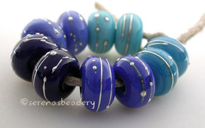 Fine Silver Blues A set of blue colored lampwork beads with 5 different pairs. From top left going counter-clockwise - light turquoise, light cobalt, dark cobalt, dark periwinkle or dark turquoise. Each silver wrap is carefully burnished onto the glass bead while it is still hot. Bead Size: 6x11 mm Amount: 10 Beads Hole Size: 2.5 mm Also available in a 7x14 mm size for .00 extra. Glossy,6x11mm,Glossy,7x14mm,Matte,6x11mm,Matte,7x14mm