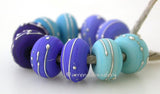 Fine Silver Blues A set of blue colored lampwork beads with 5 different pairs. From top left going counter-clockwise - light turquoise, light cobalt, dark cobalt, dark periwinkle or dark turquoise. Each silver wrap is carefully burnished onto the glass bead while it is still hot. Bead Size: 6x11 mm Amount: 10 Beads Hole Size: 2.5 mm Also available in a 7x14 mm size for .00 extra. Glossy,6x11mm,Glossy,7x14mm,Matte,6x11mm,Matte,7x14mm