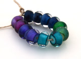 Gypsy Rainbow Gypsy Rainbow in dreamy watercolors - the color will not total even throughout the bead. These are designed to have pooling of color under the layer of clear. There is a pair each in black, steel blue, green, aqua, purple, and pink. Each has a white heart or center and is cased in clear. You can order each color separately or the set of 12 beads as shown. Bead Size: 7x12 mm Amount: 12 Beads Hole Size: 2.5 mm Glossy,Black,Glossy,Steel Blue,Glossy,Green,Glossy,Aqua,Glossy,Purple,Glossy,Pink,Glos