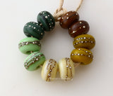Leafy Silver Dots Set This opaque set consists of deep sage green, light mint green, cream, mustard yellow, and chocolate brown. Each bead is decorated with fine silver dots that are carefully applied in the flame.Bead Size:6x11 mmAmount:10 BeadsHole Size:2.5 mm Glossy,Matte