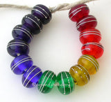 Rainbow Silver Wrapped Rondelle Set A set of rainbow rondelles pairs wrapped in fine silver. The colors range from red, orange, yellow, green, blue, indigo, and violet. Since the violet is so dark it is layered over white. 6x11mm price is per set of 14 beads Glossy,Matte