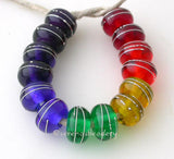 Rainbow Silver Wrapped Rondelle Set A set of rainbow rondelles pairs wrapped in fine silver. The colors range from red, orange, yellow, green, blue, indigo, and violet. Since the violet is so dark it is layered over white. 6x11mm price is per set of 14 beads Glossy,Matte