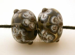 Gray Silvered Ivory Flowers a pair of transparent gray beads with black and silvered ivory flowers and adamantium centers6x12 mmmade on a 1/16, mandrelalso available with opaque grey Glossy,Matte